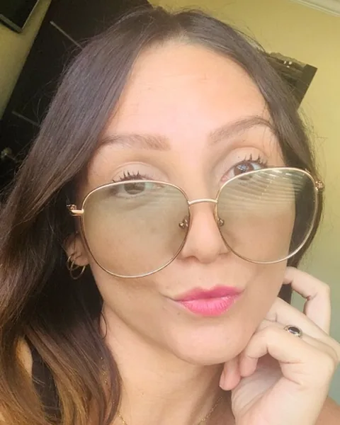 Woman in round glasses resting her chin on her hand