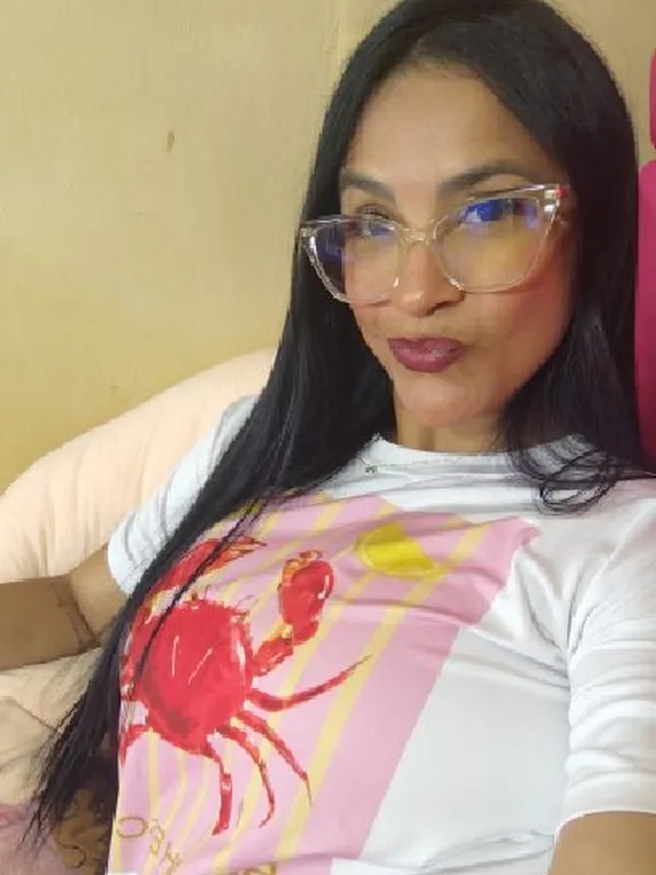 Woman in glasses and a crab-print T-shirt sitting on a sofa
