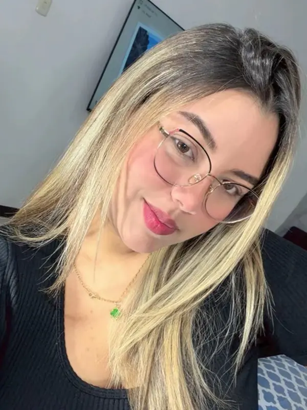 Blonde woman in glasses smiling at the camera in a bright room